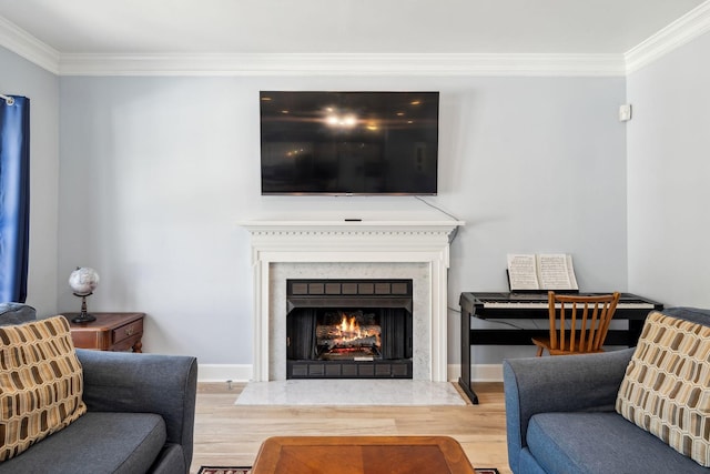 living area featuring ornamental molding, a fireplace, baseboards, and wood finished floors