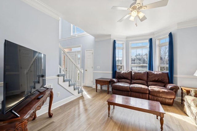 living room featuring baseboards, a ceiling fan, ornamental molding, wood finished floors, and stairs