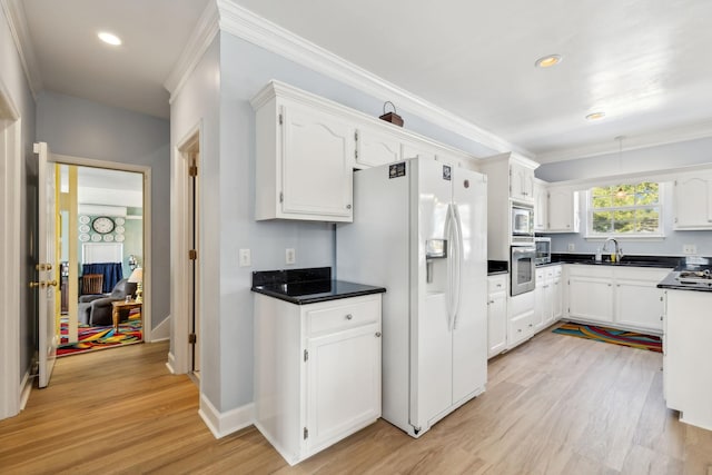 kitchen with stainless steel appliances, ornamental molding, light wood-style floors, and white cabinets