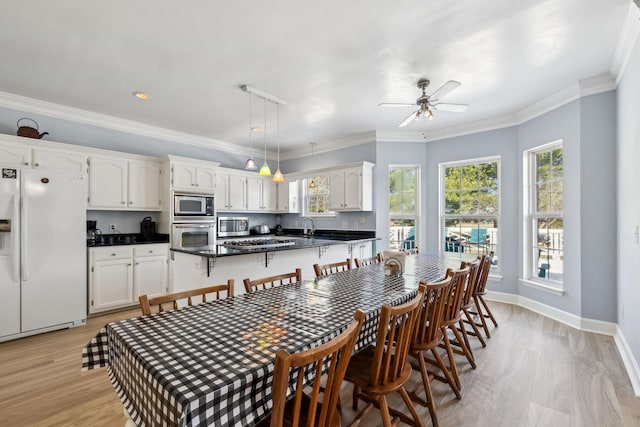 dining room featuring baseboards, ceiling fan, ornamental molding, and light wood-style floors