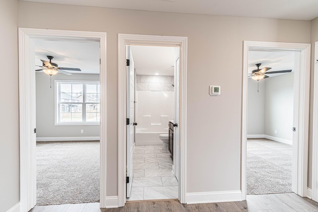 hall featuring carpet flooring and baseboards