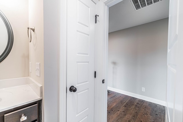 bathroom with visible vents, vanity, baseboards, and wood finished floors