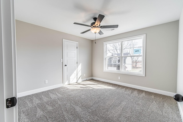 carpeted empty room featuring a ceiling fan, visible vents, and baseboards