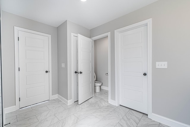 unfurnished bedroom featuring marble finish floor and baseboards