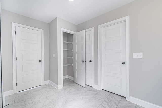 unfurnished bedroom featuring marble finish floor and baseboards