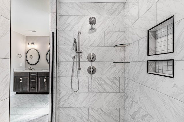 full bathroom with visible vents, a tile shower, and vanity