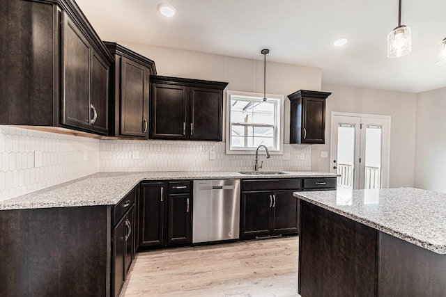 kitchen with tasteful backsplash, light wood-style flooring, a sink, light stone countertops, and dishwasher