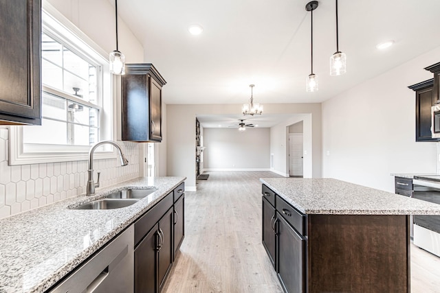 kitchen with a sink, light wood-style floors, dark brown cabinets, stainless steel dishwasher, and decorative backsplash