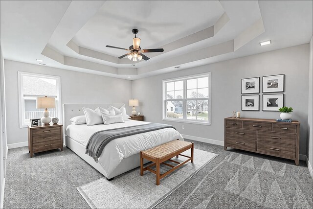 bedroom with carpet floors, a tray ceiling, a ceiling fan, and baseboards