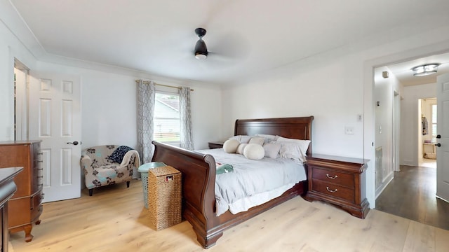 bedroom featuring a ceiling fan, crown molding, and light wood-style flooring