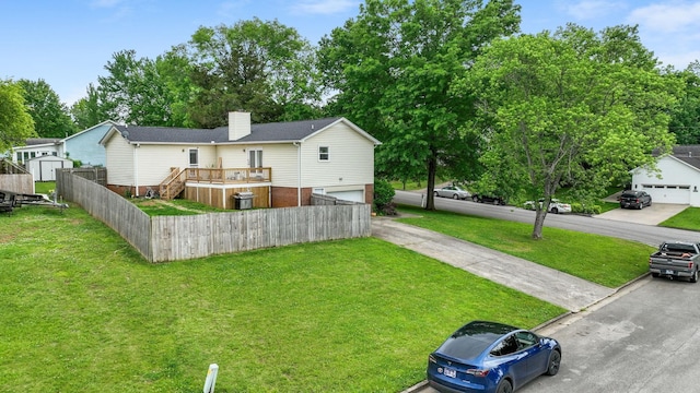 view of yard with a deck, an attached garage, fence, and an outdoor structure