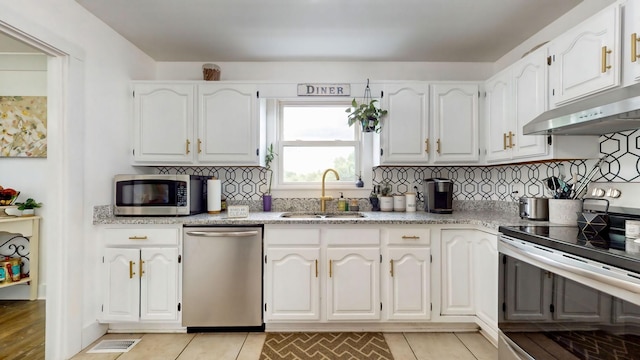 kitchen with stainless steel appliances, a sink, white cabinets, and under cabinet range hood