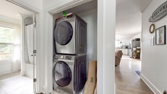 laundry area with laundry area, stacked washing maching and dryer, and baseboards