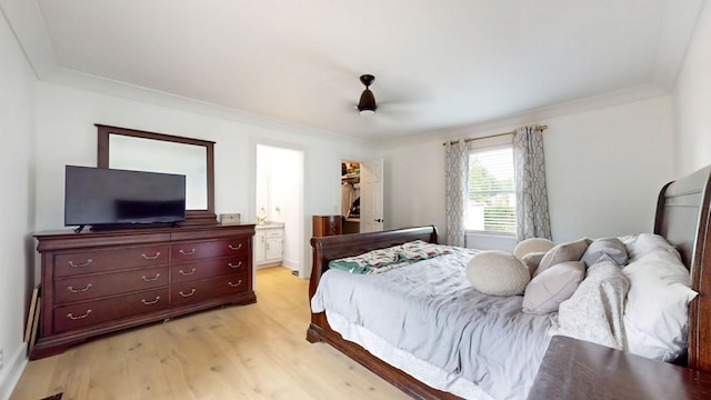 bedroom with light wood finished floors, ensuite bath, a spacious closet, crown molding, and a closet