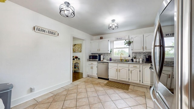 kitchen featuring white cabinetry, appliances with stainless steel finishes, tasteful backsplash, and light tile patterned flooring