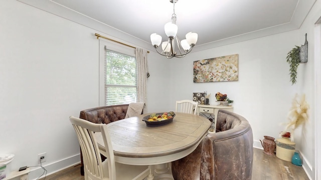 dining room featuring wood finished floors, crown molding, baseboards, and an inviting chandelier