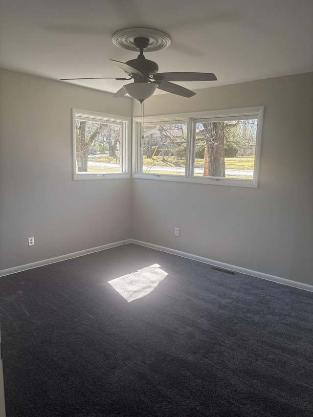 spare room with baseboards, dark colored carpet, and a healthy amount of sunlight