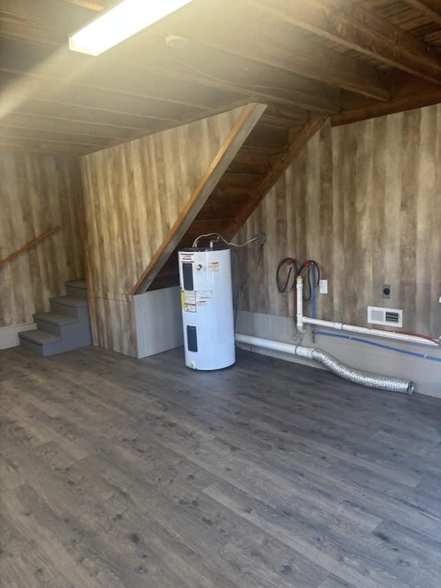 below grade area featuring stairs, visible vents, wood finished floors, and electric water heater