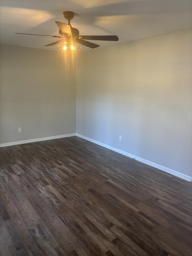 unfurnished room featuring dark wood-style floors, a ceiling fan, and baseboards