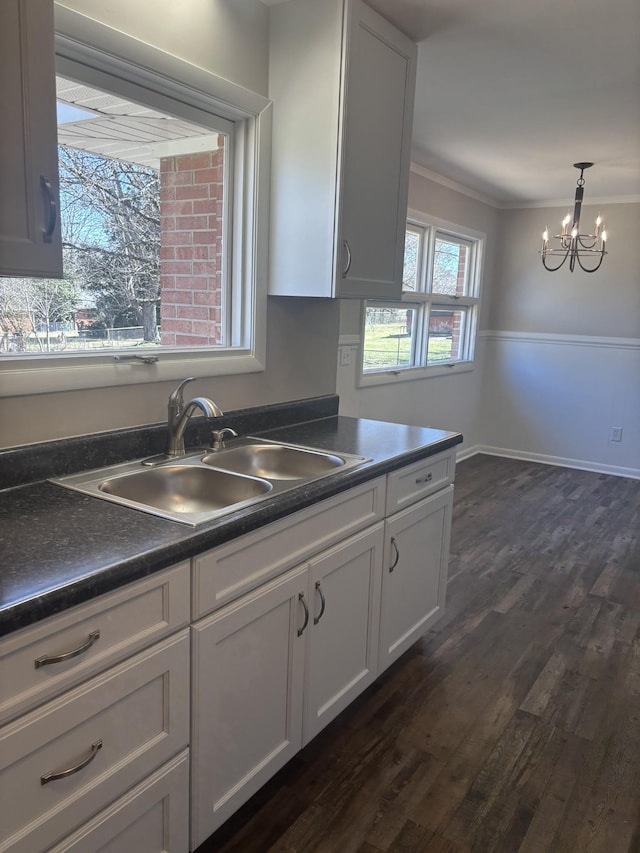 kitchen with dark countertops, a sink, white cabinets, and crown molding