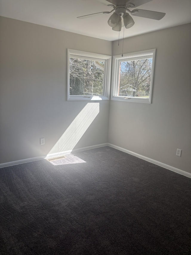 spare room with ceiling fan, dark carpet, and baseboards