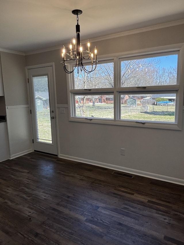 unfurnished dining area featuring dark wood-style floors, a chandelier, crown molding, and baseboards