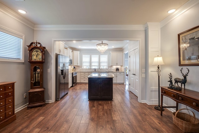 kitchen with tasteful backsplash, dark wood-style floors, a kitchen island, appliances with stainless steel finishes, and white cabinetry