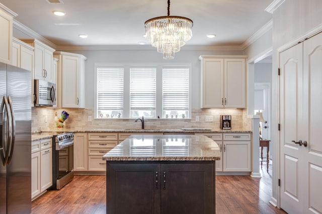 kitchen featuring hardwood / wood-style flooring, crown molding, appliances with stainless steel finishes, and a sink