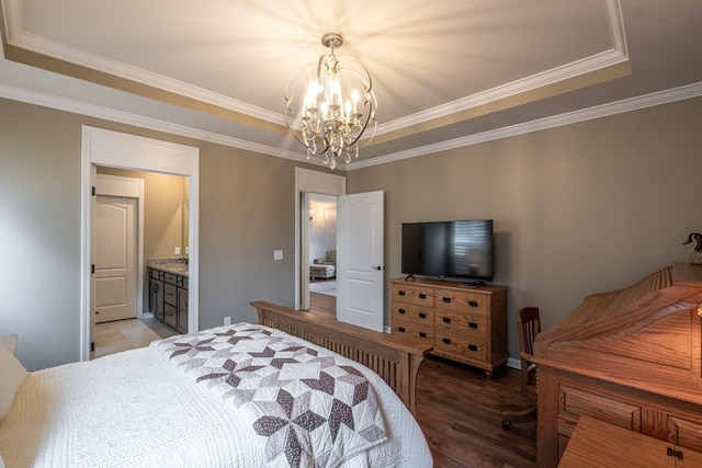 bedroom with ornamental molding, wood finished floors, ensuite bathroom, a tray ceiling, and a chandelier