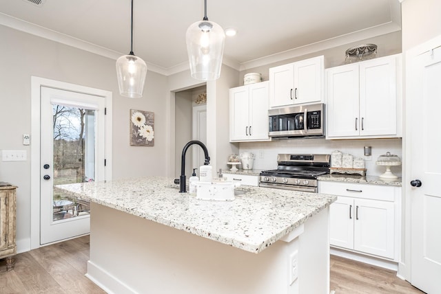 kitchen with light stone countertops, light wood-style floors, ornamental molding, and appliances with stainless steel finishes