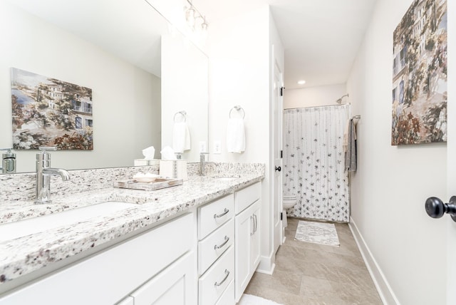 bathroom with toilet, a sink, a shower with curtain, baseboards, and double vanity