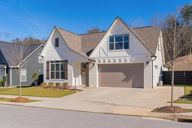 view of front of property with a shingled roof, fence, concrete driveway, and a front yard