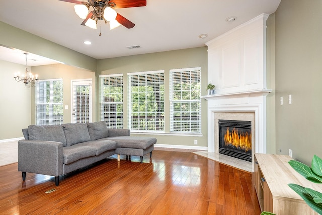 living room with wood-type flooring, visible vents, baseboards, and a high end fireplace