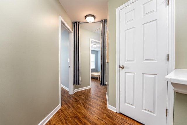 corridor featuring dark wood-style floors and baseboards