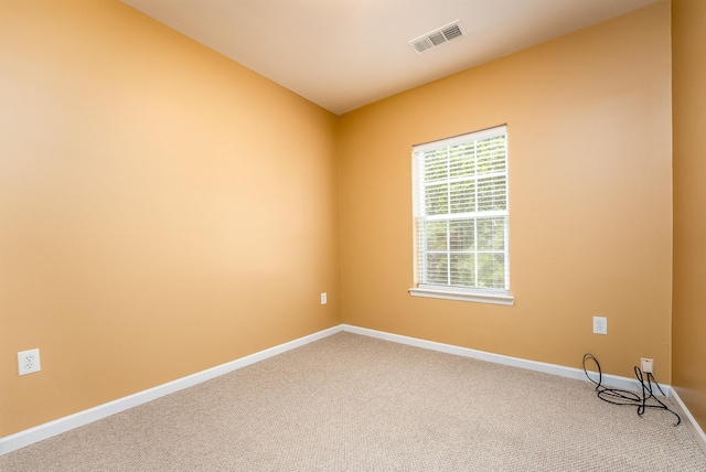 spare room with carpet floors, visible vents, and baseboards