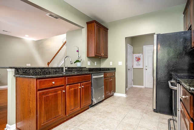 kitchen with visible vents, dark stone countertops, a peninsula, stainless steel appliances, and a sink