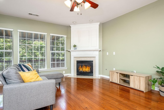 living room featuring visible vents, baseboards, hardwood / wood-style flooring, ceiling fan, and a fireplace