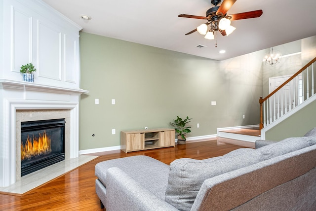 living room with visible vents, a high end fireplace, wood finished floors, baseboards, and stairs