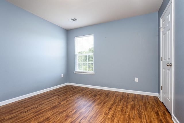 unfurnished room with dark wood finished floors, visible vents, and baseboards