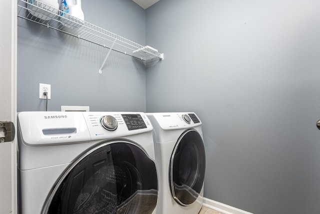 washroom featuring laundry area, washing machine and dryer, and baseboards