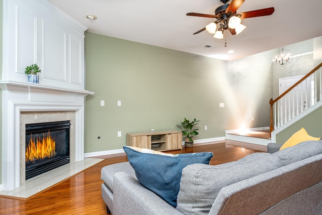 living area featuring baseboards, a premium fireplace, visible vents, and wood finished floors