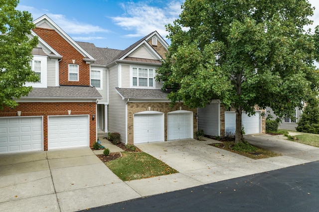 townhome / multi-family property with a garage, concrete driveway, brick siding, and a shingled roof