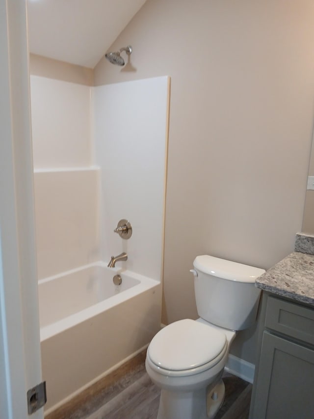 bathroom featuring shower / bath combination, toilet, lofted ceiling, wood finished floors, and vanity