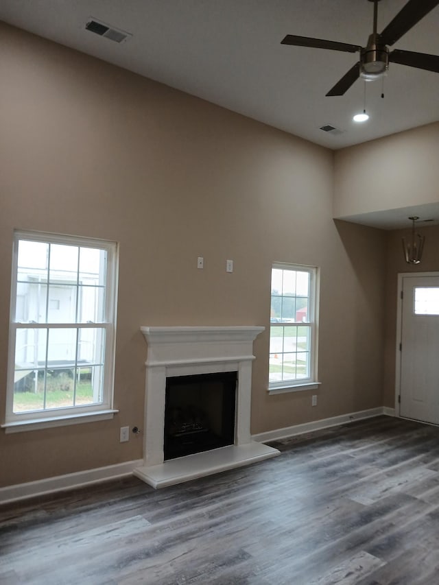 unfurnished living room with a fireplace with raised hearth, visible vents, and a healthy amount of sunlight