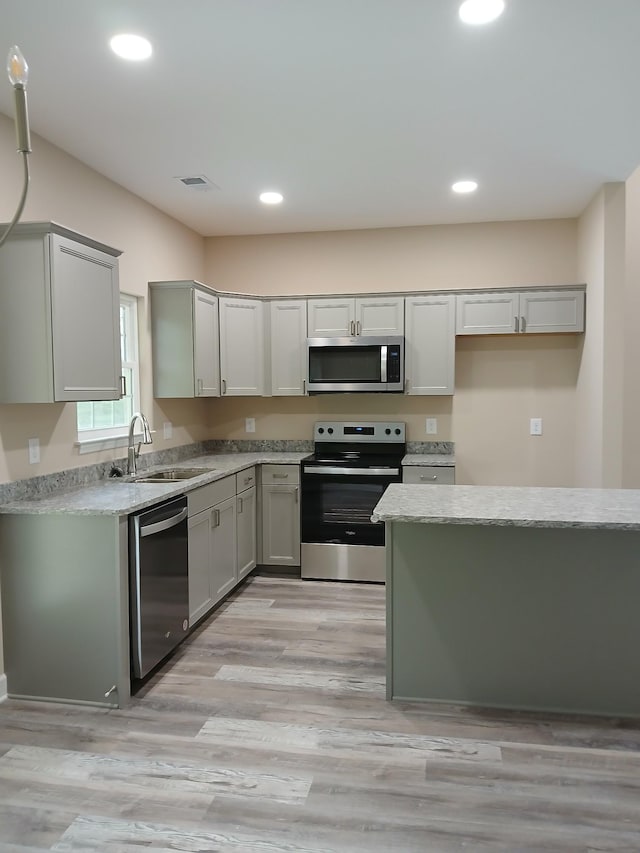 kitchen with appliances with stainless steel finishes, gray cabinets, a sink, and recessed lighting