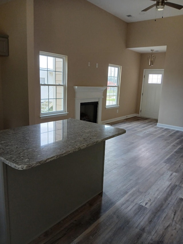 unfurnished living room featuring a ceiling fan, a fireplace, baseboards, and wood finished floors