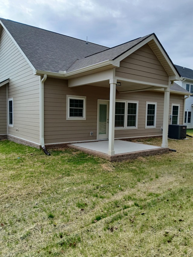 back of house with a yard, roof with shingles, central AC, and a patio