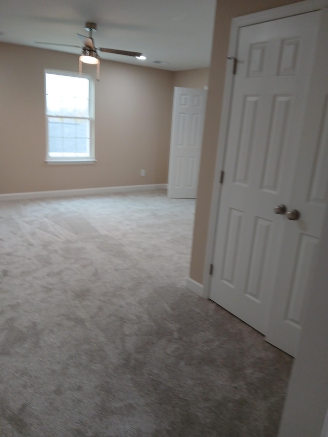 carpeted spare room with ceiling fan and baseboards