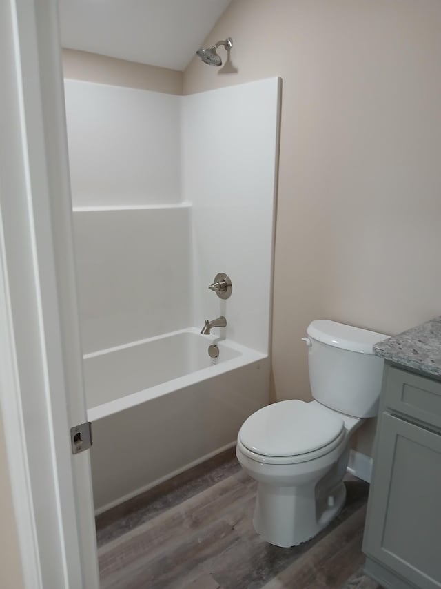 full bath with toilet, bathtub / shower combination, wood finished floors, and vanity