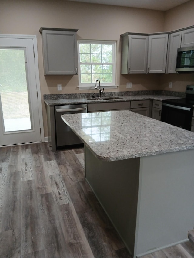 kitchen featuring wood finished floors, a sink, appliances with stainless steel finishes, gray cabinets, and light stone countertops